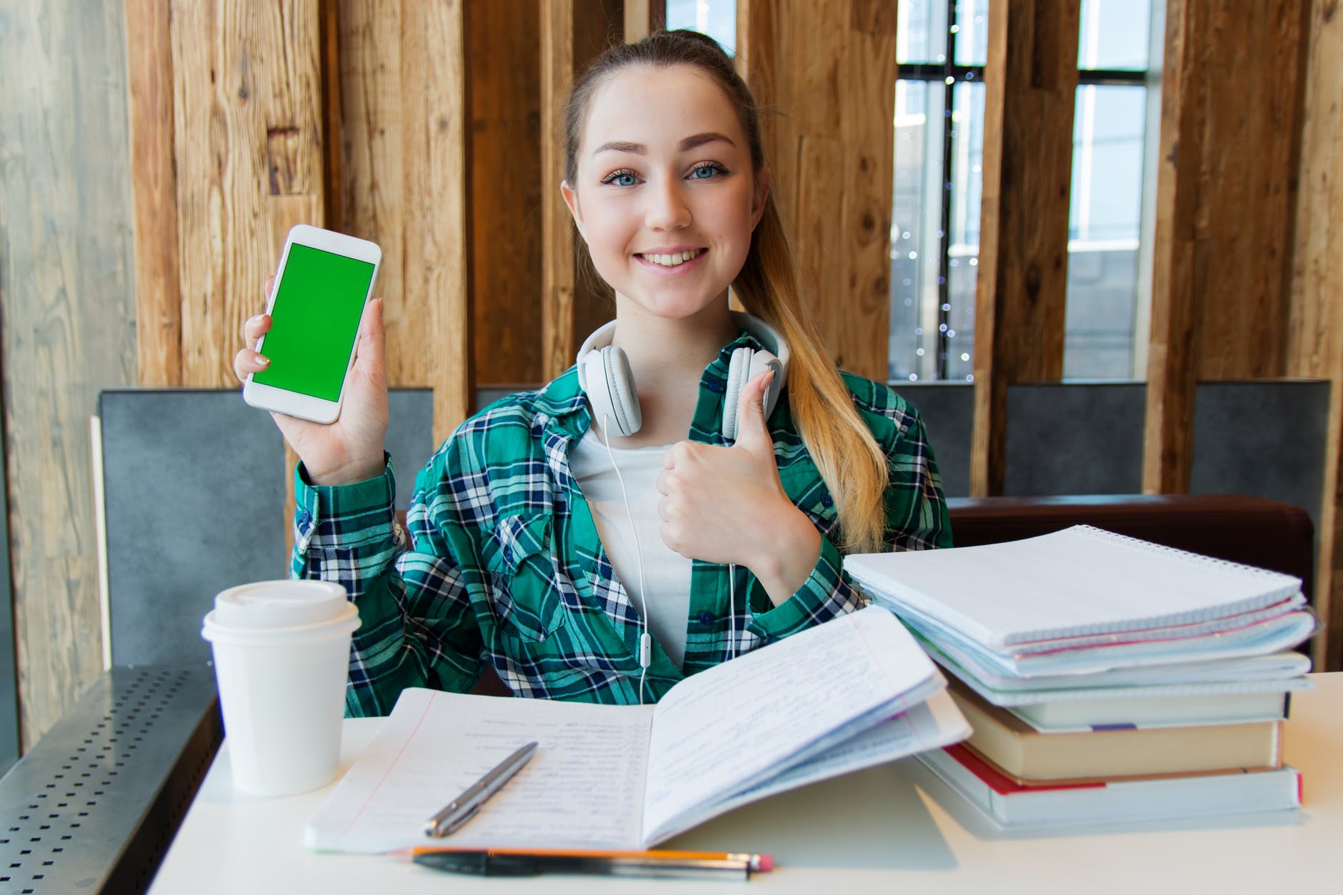 smiling woman holding white android smartphone while sitting front of table